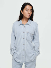Model wearing Desert Shirt in light blue, oversized fit with brushed silver buttons and a curved hem.