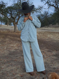 Model standing outdoors in a Desert Shirt with oversized fit and curved hem, styled with a wide-brim hat.