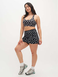 Model standing in polka dot Doing Things Bra in Black with mesh backing and removable pads, styled for activewear.
