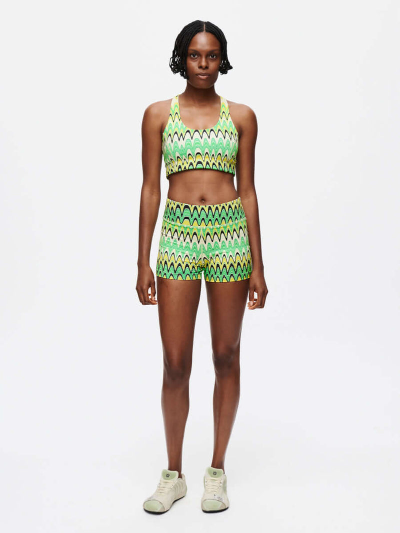 Model wearing Doing Things Bra with matching shorts in vibrant green zigzag pattern, for activewear.