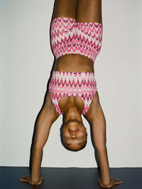 Model doing a handstand in Doing Things Bra with colorful zigzag pattern, with the high-performance design.