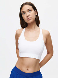 Model wearing Doing Things Bra in White, featuring a scoop neckline and supportive fit for active workouts.