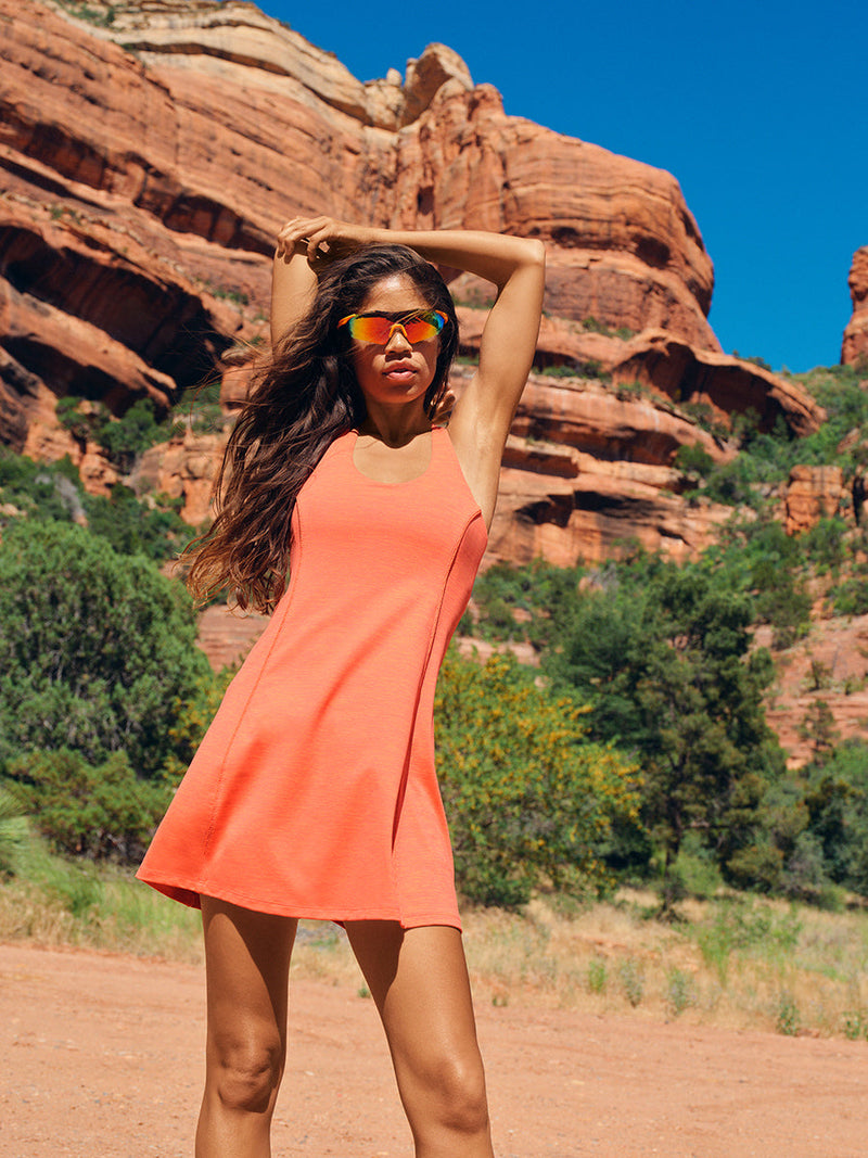 Model posing outdoors in Doing Things Dress, vibrant coral color with a sporty fit, ideal for active lifestyles.
