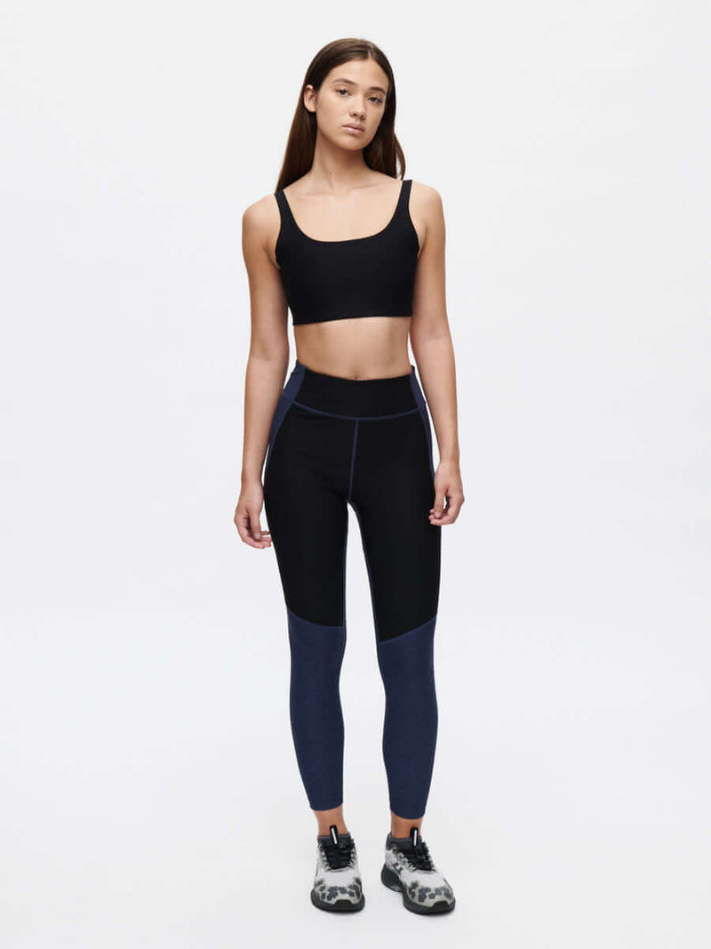 Model wearing Double Time Bra in Black with medium support and paired with high-waisted leggings for activewear.