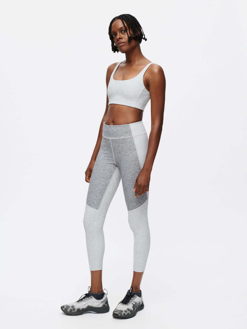 Model in a relaxed pose wearing Double Time Bra in Light Gray, with textured compression fabric for medium support.