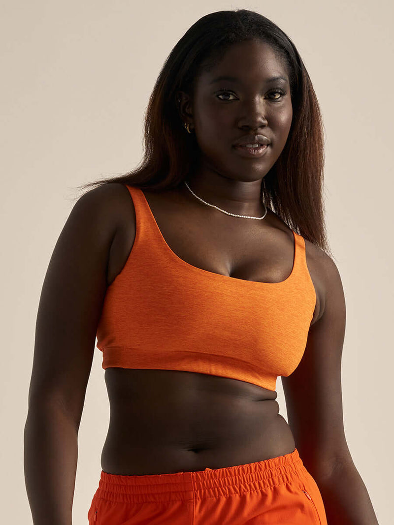 Model wearing Double Time Bra in Bright Orange, featuring a snug fit and low scoop design.