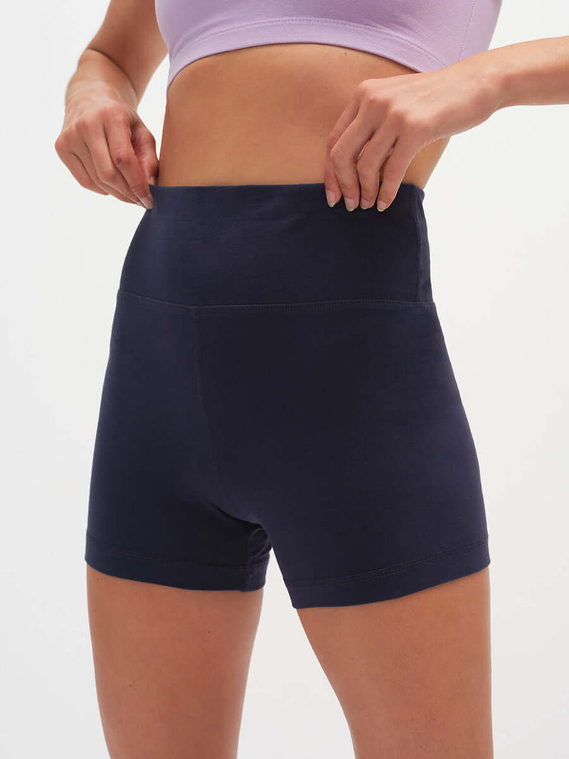 Model adjusting waistband of Echo 3.5" Short in Navy, featuring a tall waistband for gentle hold.
