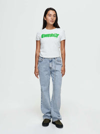 Model standing in Energy Tee in White, featuring a bold ENERGY graphic in bright green.