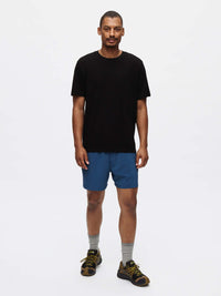 Model standing in Everyday Classic Shortsleeve in Black, paired with blue shorts for active recreation.
