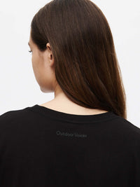 A woman with long hair wearing an Everyday Shortsleeve tee, with the back design from Outdoor Voices.