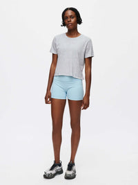 Model standing in Everyday Shortsleeve in Grey with relaxed fit and slight crop, paired with shorts.