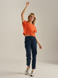 Model raising her arm in Everyday Shortsleeve in Orange, featuring a relaxed fit and slight crop for everyday wear.
