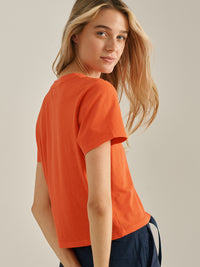 Model showing Everyday Shortsleeve in Bright Orange, relaxed fit with slight crop from the back.