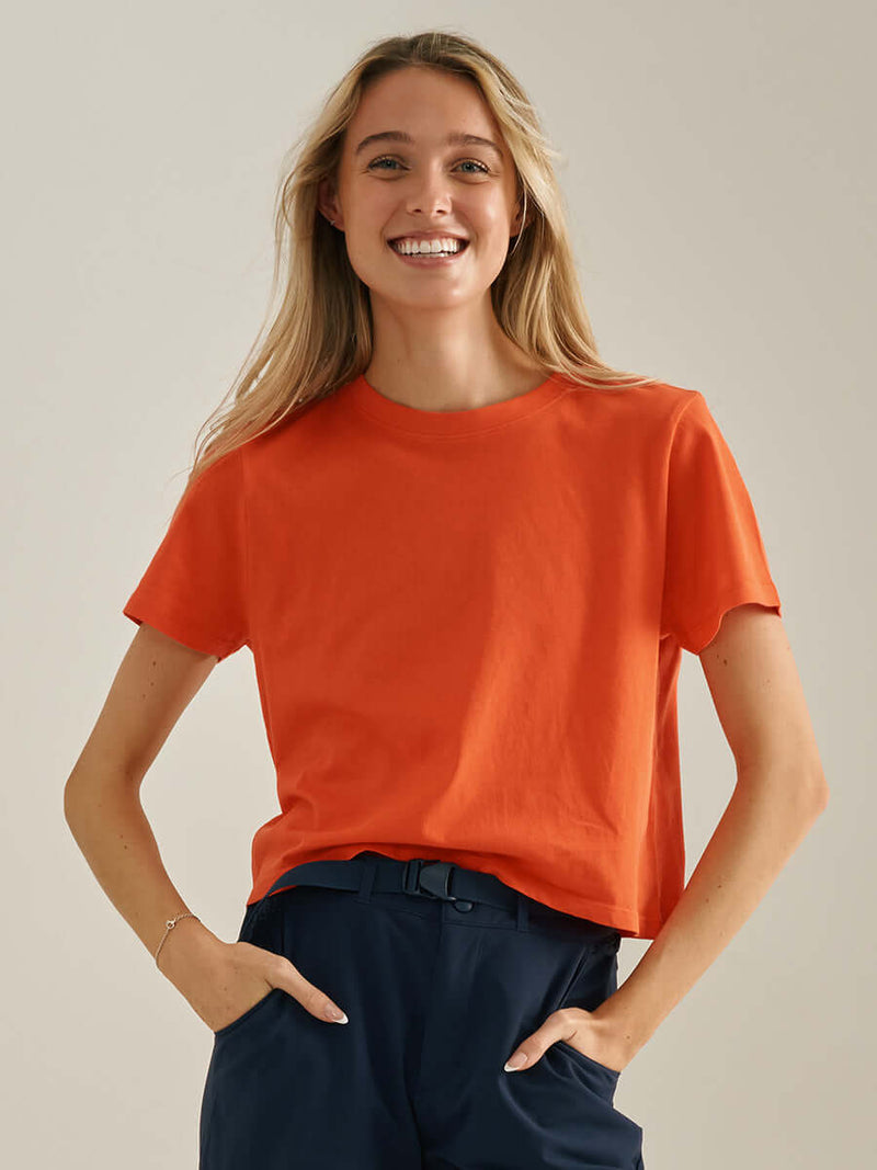 Model smiling in Everyday Shortsleeve in Orange, featuring a relaxed fit and slight crop.