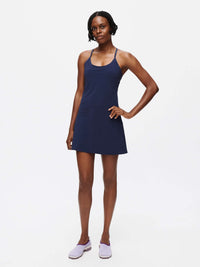 Model wearing The Exercise Dress in Navy with adjustable straps and a built-in shorts liner for activewear.