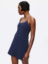 Model in profile wearing The Exercise Dress in Navy with adjustable straps and a built-in shorts liner.