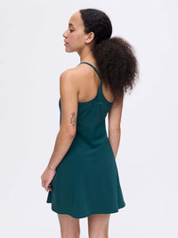 Back view of The Exercise Dress in Forest Green with adjustable straps and a flowy skirt, styled for active wear.