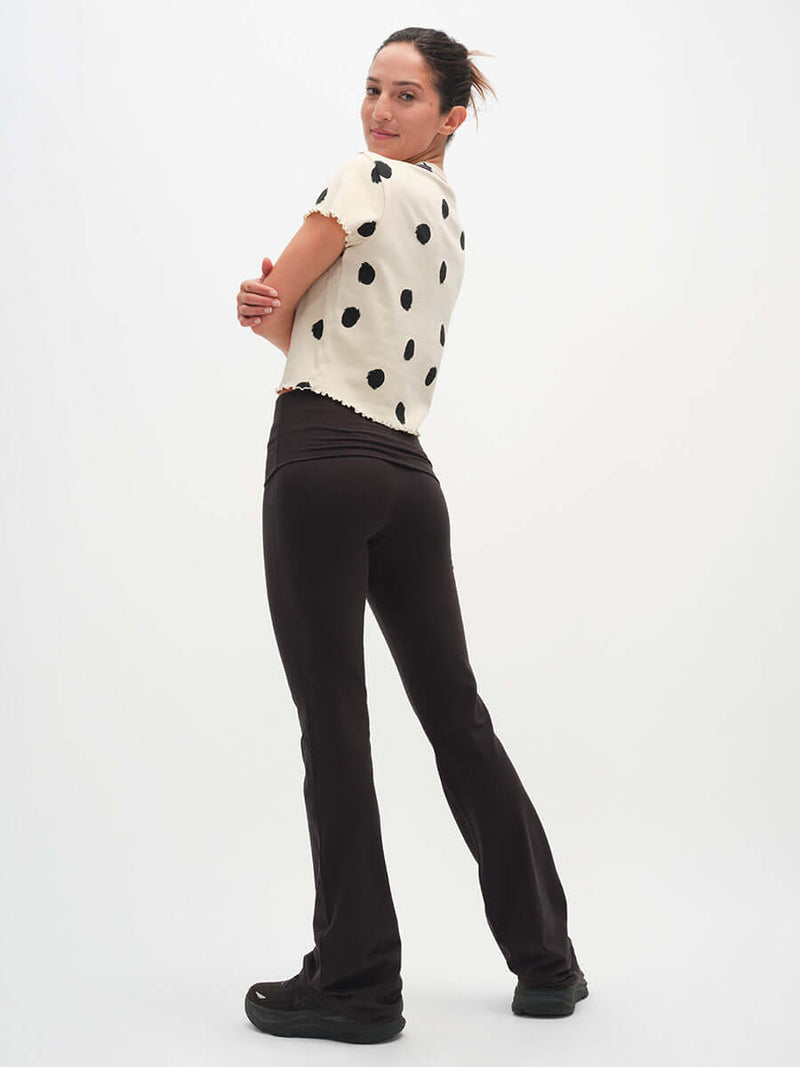 Model seen from behind wearing Flared Legging in Black with extra-tall waistband, styled casually.
