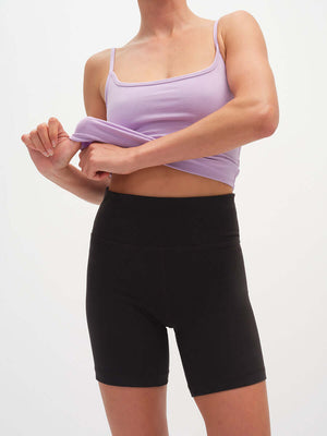 Model adjusting top while wearing Echo 5.5" Short in Cotton Candy, high rise with tall waistband.