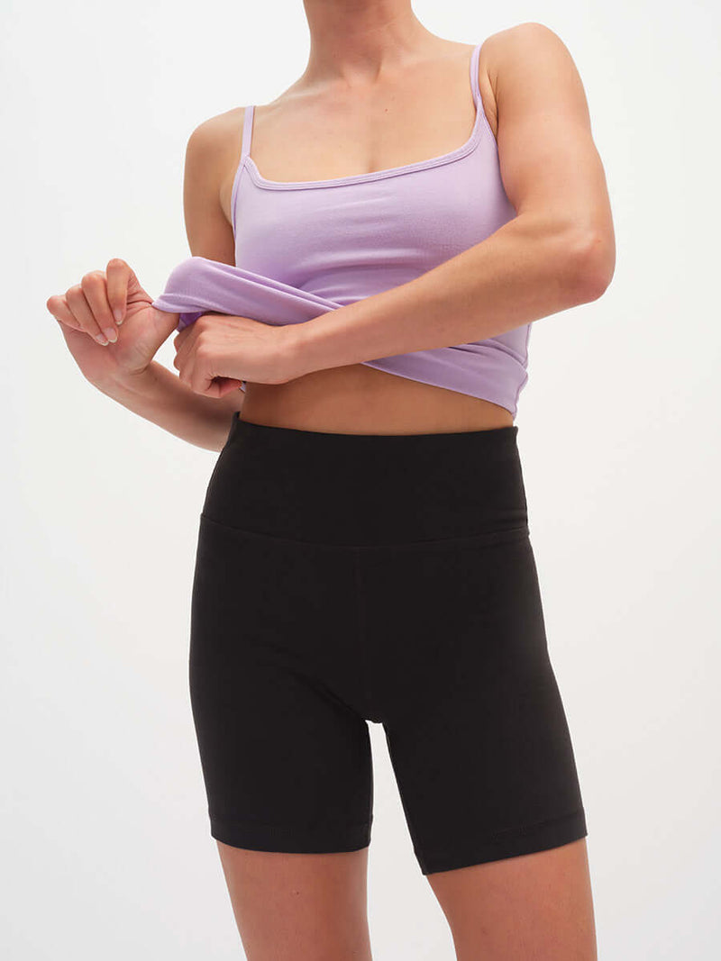 Model adjusting top while wearing Echo 5.5" Short in Cotton Candy, high rise with tall waistband.