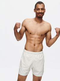 Model flexing in High Stride 5" Short with Pockets in Cream, with lightweight fabric and comfortable fit.