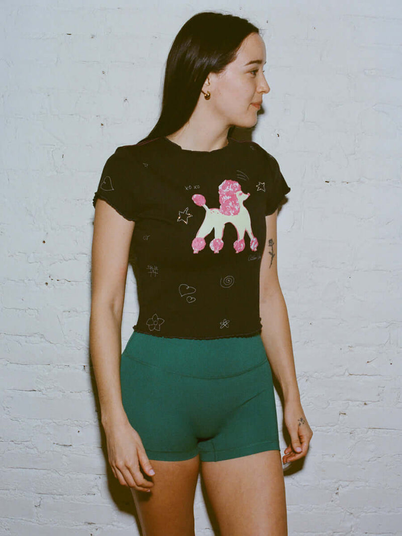 Model standing in side profile wearing Joggy Doggy Tee in Black, featuring playful dog print and scrapbook scribbles.