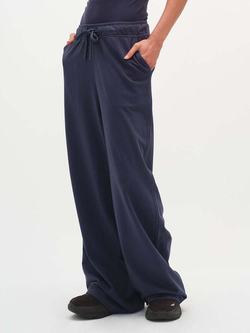 Model posing in Malibu Sweatpant in Navy, with wide leg design and side pockets.