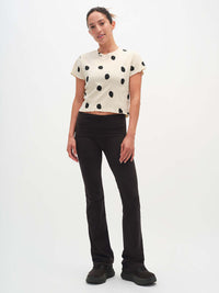 Model standing in Polka Tee with black polka dots, with the lettuce edge finish and relaxed fit.