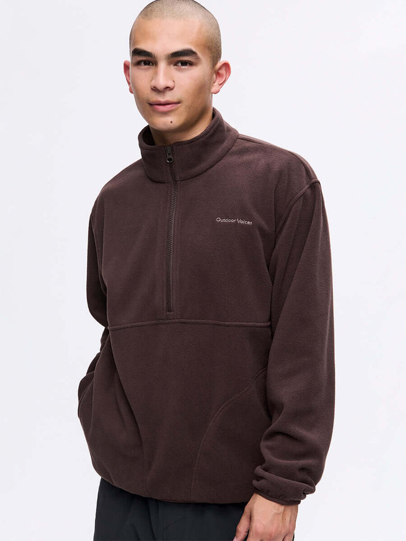 Model wearing RecFleece 1/2 Zip in Dark Brown, relaxed fit with a front ½ zip and side pockets.