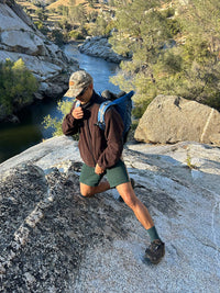 Person hiking in a rocky area wearing RecFleece Relaxed Full Zip in Black, with a relaxed fit and backpack.
