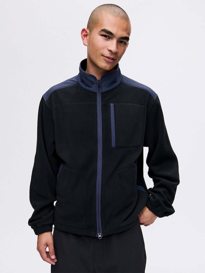 Model wearing RecFleece Relaxed Full Zip in Black, featuring contrast shoulder panels and chest pocket.