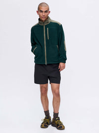 Model standing in RecFleece Relaxed Full Zip in Dark Green, featuring a chest pocket and soft fleece fabric.