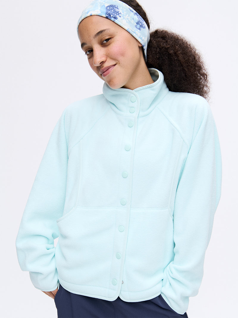 Model smiling in light blue RecFleece Snap Jacket with snap front and spacious dolman sleeves.