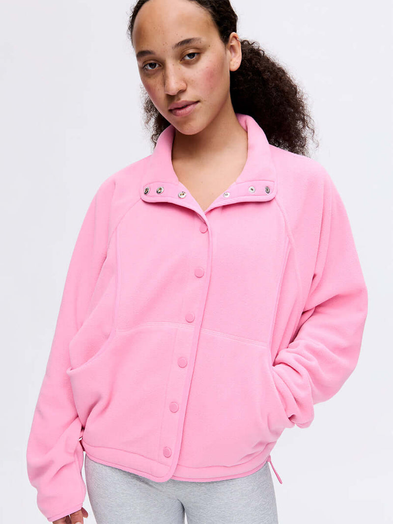 Model wearing RecFleece Snap Jacket in Pink with a snap-up front and dolman sleeves, styled for everyday wear.