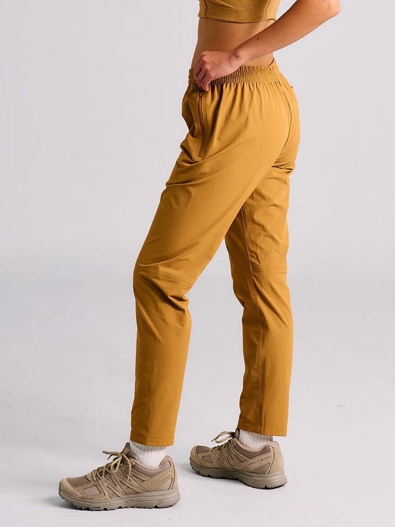 Model in profile wearing RecTrek 26" Pant in Gold, featuring an elastic waistband and lightweight fabric.