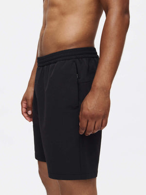 Model side view wearing RecTrek 7" Short in Black, featuring adjustable drawstring and zippered pockets.