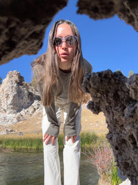 Model peering through rocks, wearing RecTrek Cargo Pant in Light Beige, with relaxed fit for outdoor adventures.