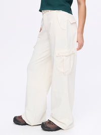 Model in a relaxed pose wearing RecTrek Cargo Pant in Cream, featuring utility-style pockets and a belted waistband.