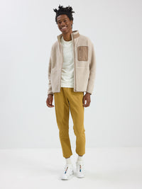 Model smiling and standing in RecTrek Pant in Mustard, relaxed fit with drawstring and zippered pockets.