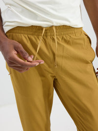 Close-up view of a model wearing RecTrek Pant in mustard yellow with a custom-fit drawstring and relaxed fit.