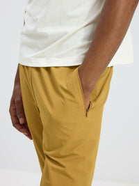 Close-up of model's hand in pocket of RecTrek Pant in Mustard, featuring zippered pockets for storage.