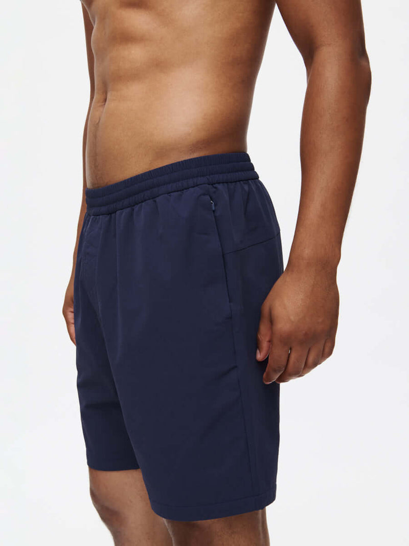 Side view of model wearing RecTrek 7" Short in Navy with adjustable drawstring and zippered pockets.