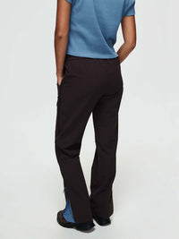 Model in a blue top wearing RecTrek Zip Pant in Dark Brown with mesh ventilation panels and wider leg.