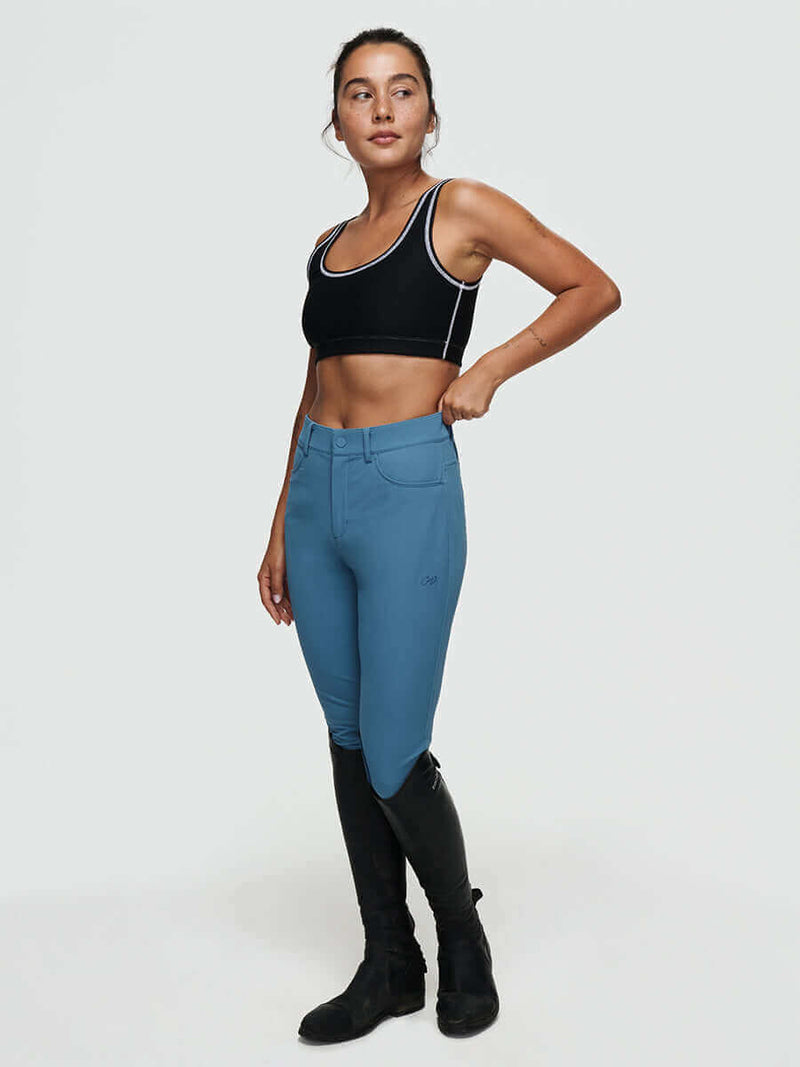 Woman wearing stretchy riding gear with the Ride Pant, for comfort and durability while riding.