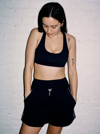 Model wearing Sport Short in Black with wide leg design and pockets, styled for casual wear.