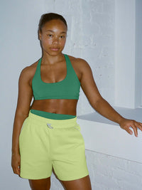 Model in sporty pose wearing Sport Short in vibrant yellow with an adjustable waistband for a comfortable fit.