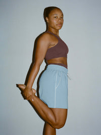 Model stretching while wearing Sport Short in Light Blue, with a technical nylon waistband for comfort.