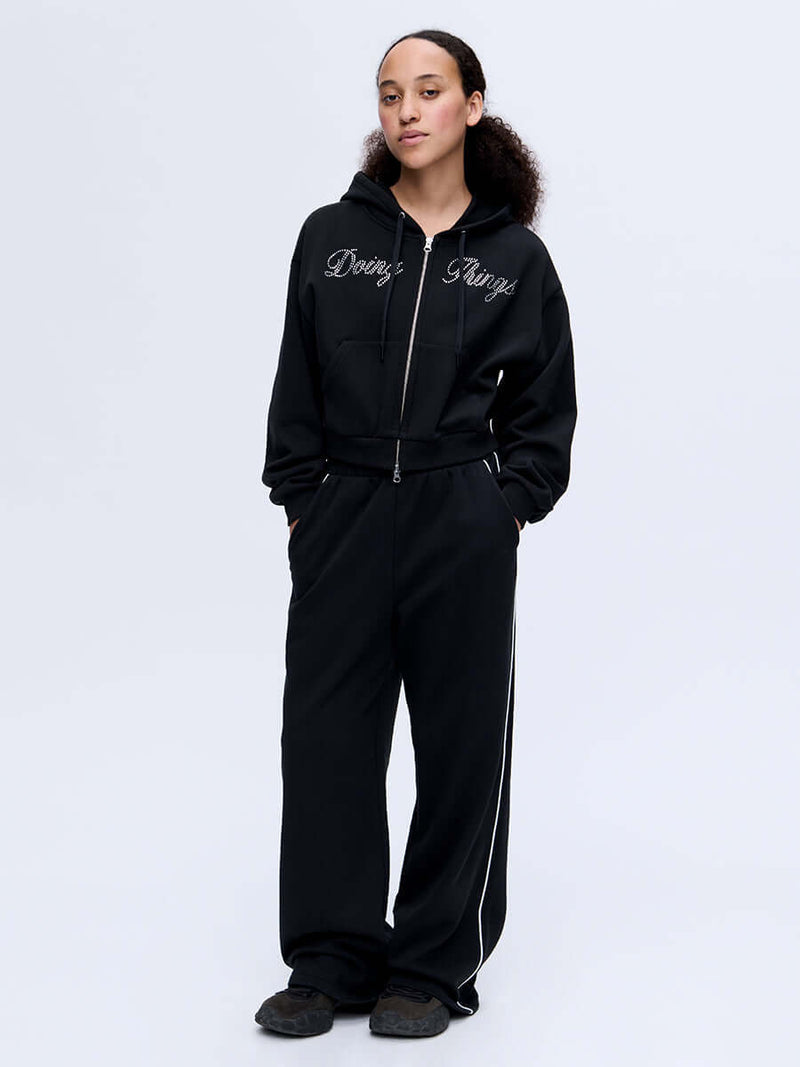 Model wearing Sport Sweatpant in Black, featuring a relaxed wide leg fit and playful bungee cord waistband.