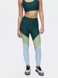 Model posed standing in Springs 7/8 Legging with three-tone paneling and a fitted silhouette, styled for activewear.