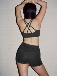 Back view of model wearing Star Bra in Black, featuring intersecting straps and medium support.